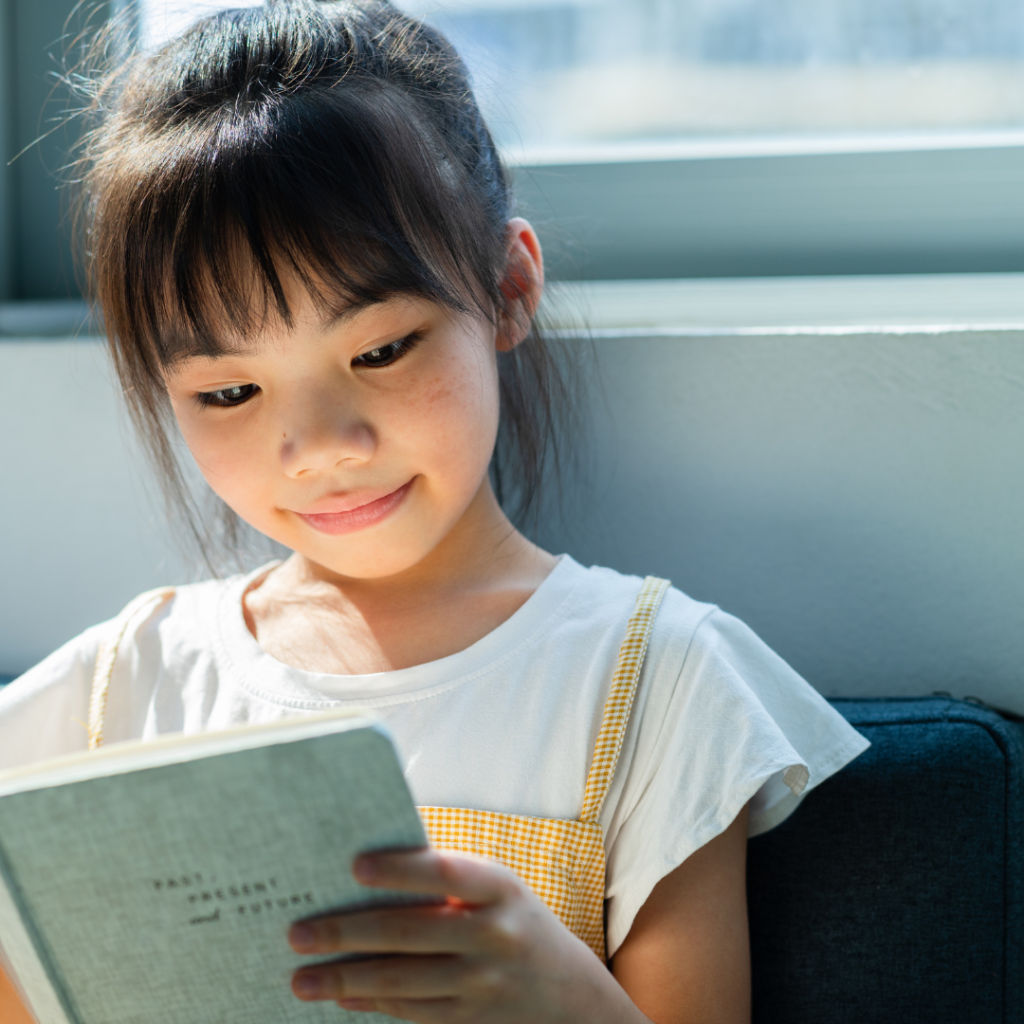 fillette asiatique lisant un livre en souriant